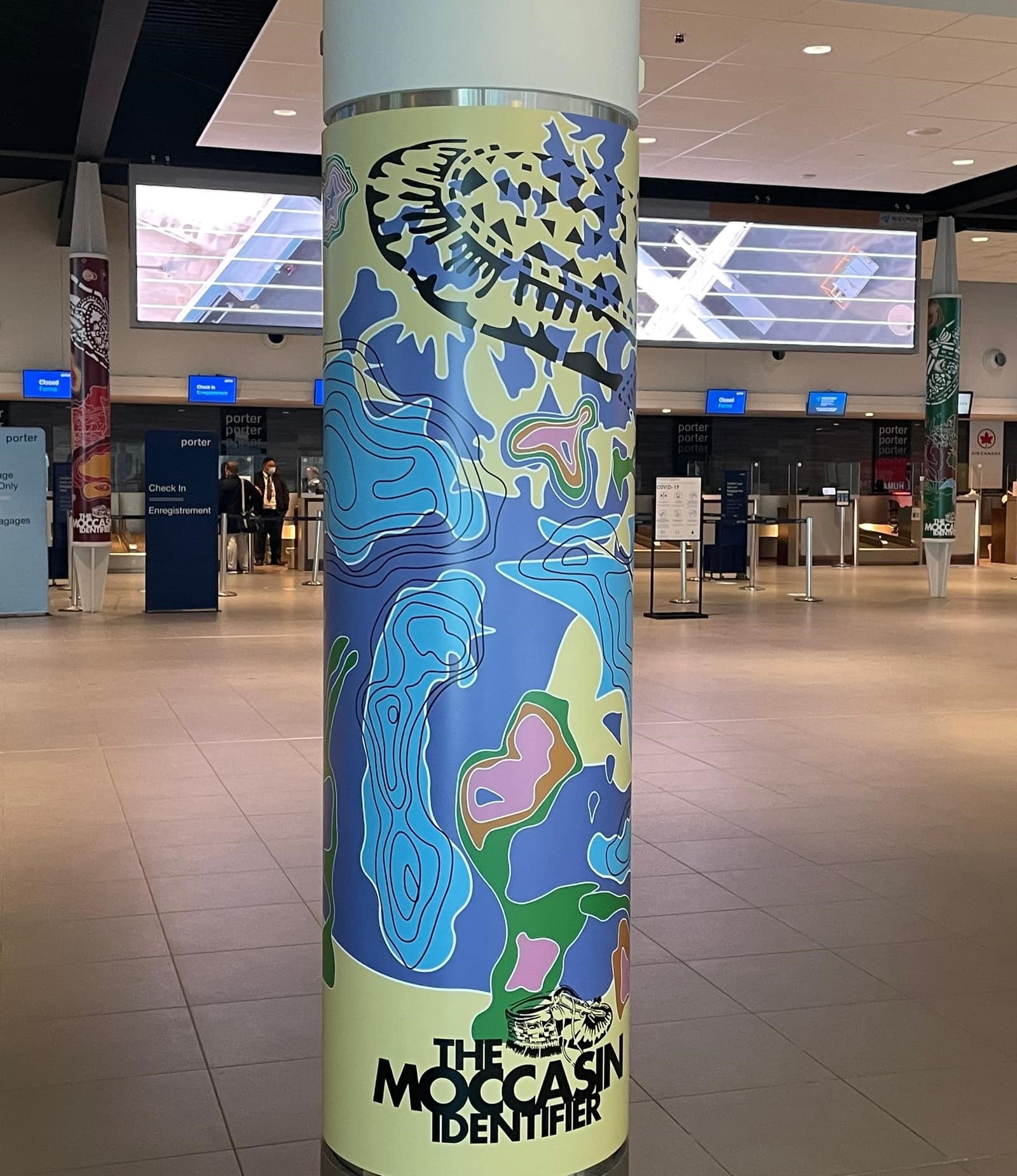 pillar in airport that is wrapped with indigenous art