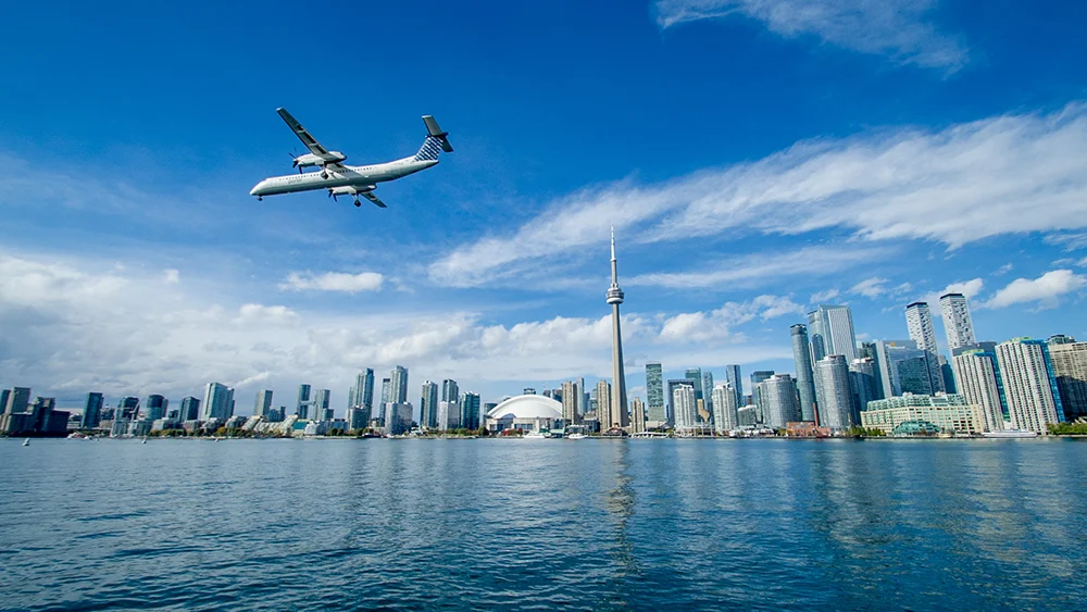 Photo of downtown Toronto with a plain in the foreground flying over lake Ontario